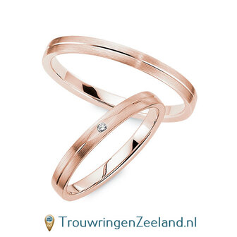 Trouwringen in 8*/14/18 karaat roodgoud mat met V-groef 2,5 mm. breed met in de damesring 1 x 0,008 ct diamant in ovalen zetting