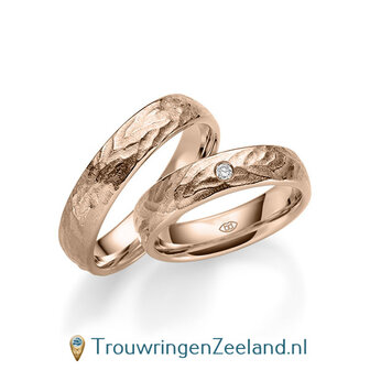 Trouwringen in 14/18 karaat ros&eacute;goud bewerkt 5 mm. breed met in de damesring 1 diamant