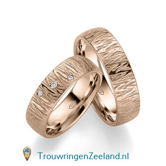 Trouwringen in 14/18 karaat roodgoud mat en glans 6,0 mm. breed met golven overdwars en in de damesring 3 diamanten schuin gezet per paar vanaf