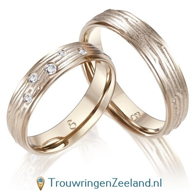 Trouwringen in 14 of 18 karaat champagnegoud met houtstructuur met in de damesring 5 diamanten fantasie gezet per paar