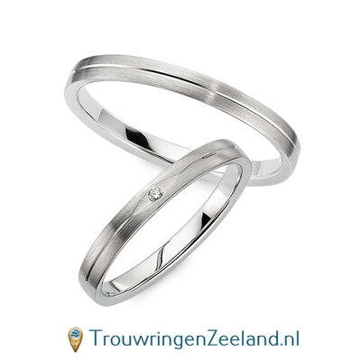 Trouwringen in 8*/14/18 karaat witgoud mat met V-groef 2,5 mm. breed met in de damesring 1 x 0,008 ct diamant in ovalen zetting