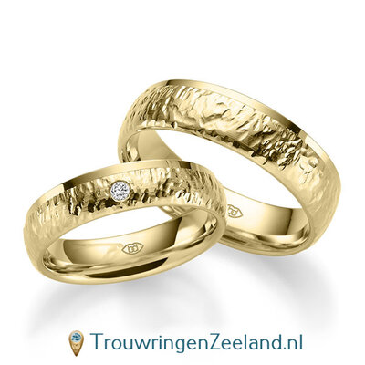 Trouwringen in 14/18 karaat geelgoud bewerkt en rand glans gepolijst 5 mm. breed met in de damesring 1 diamant