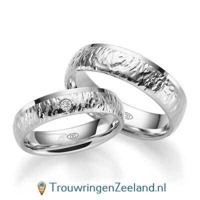 Trouwringen in 14/18 karaat witgoud bewerkt en rand glans gepolijst 5 mm. breed met in de damesring 1 diamant