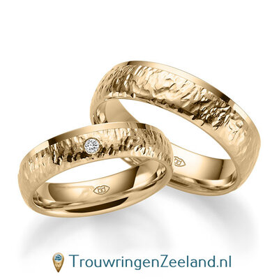 Trouwringen in 14/18 karaat roségoud bewerkt en rand glans gepolijst 5 mm. breed met in de damesring 1 diamant