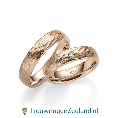 Trouwringen in 14/18 karaat roodgoud bewerkt 5 mm. breed met in de damesring 1 diamant