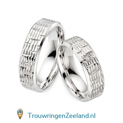 Trouwringen in 14/18 karaat witgoud glans schub structuur 6,0 mm. breedte en in de damesring 1 diamant van 0,05 ct. per paar vanaf